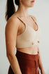 Woman wearing a beige sports bra and brown pants against a white background